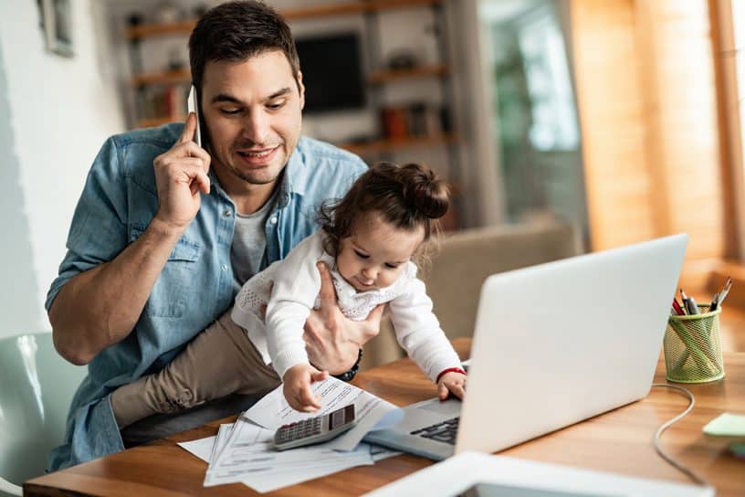 father working remotely while holding his kid
